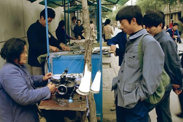 照片拍摄于1984年的西安,在街头缝纫摊位做衣服的青年,记得小时候穿的衣服都是买布料,现做的。