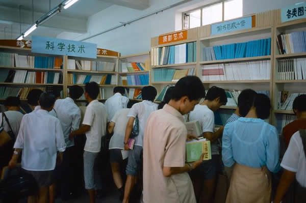 照片拍摄于1985年,北京王府井的某家书店里买书的青年男女。