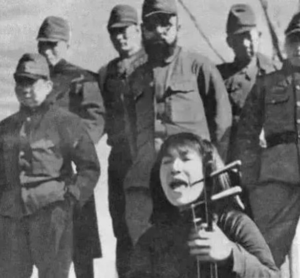 几名日本兵逼着一名中国妇女给他们拉二胡听。