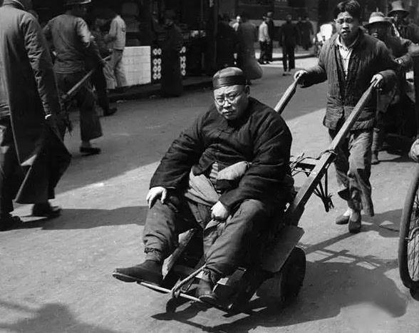 图为:1938年,上海老板让伙计用推车载他上班。